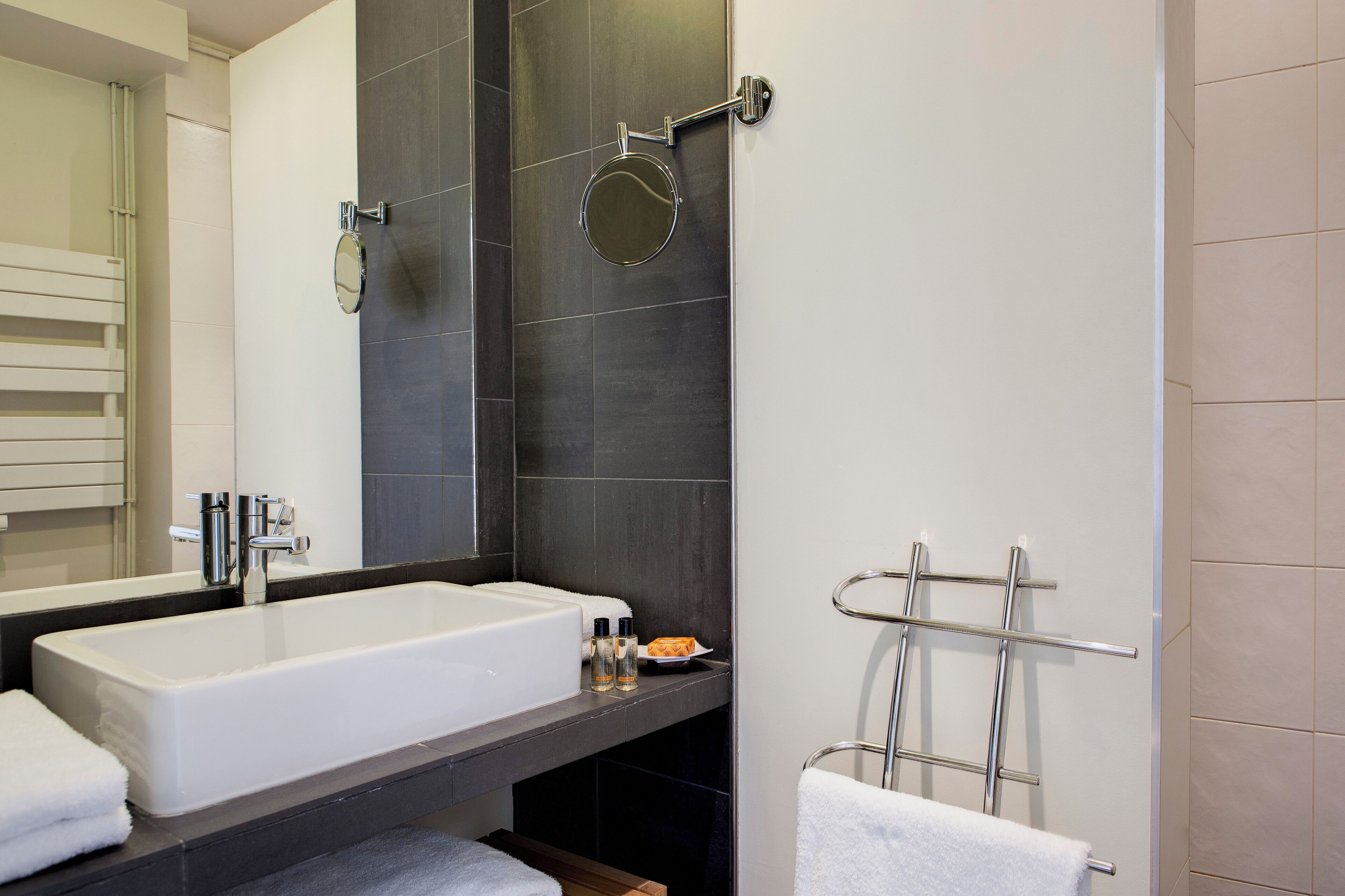 Een moderne badkamer met een groot, wit bad, een ronde spiegel en een handdoekhouder.
