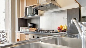 A modern kitchen with stainless steel appliances, a coffee maker, and a fruit basket on the counter. - Beauregard Design Résidence (Paris)