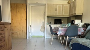 Une cuisine de taille réduite avec un coin repas, des meubles en bois et un sol carrelé.