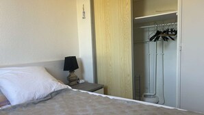 Une chambre d’hôtel comprenant un lit, une table de chevet avec une lampe, une armoire et un espace douche.