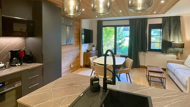 A modern kitchen with a marble countertop, a dining area with a round table and chairs, and a living area with a sofa and a TV. - Renovated apartment 4 pers, parking, Les Gets (Les Gets)
