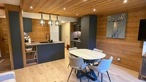 A modern kitchen with wooden accents, a dining area with a wooden table and chairs, and a mounted painting of a deer. - Renovated apartment 4 pers, parking, Les Gets (Les Gets)
