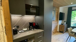 A modern kitchen with dark cabinets, a built-in oven, and a coffee maker. - Renovated apartment 4 pers, parking, Les Gets (Les Gets)