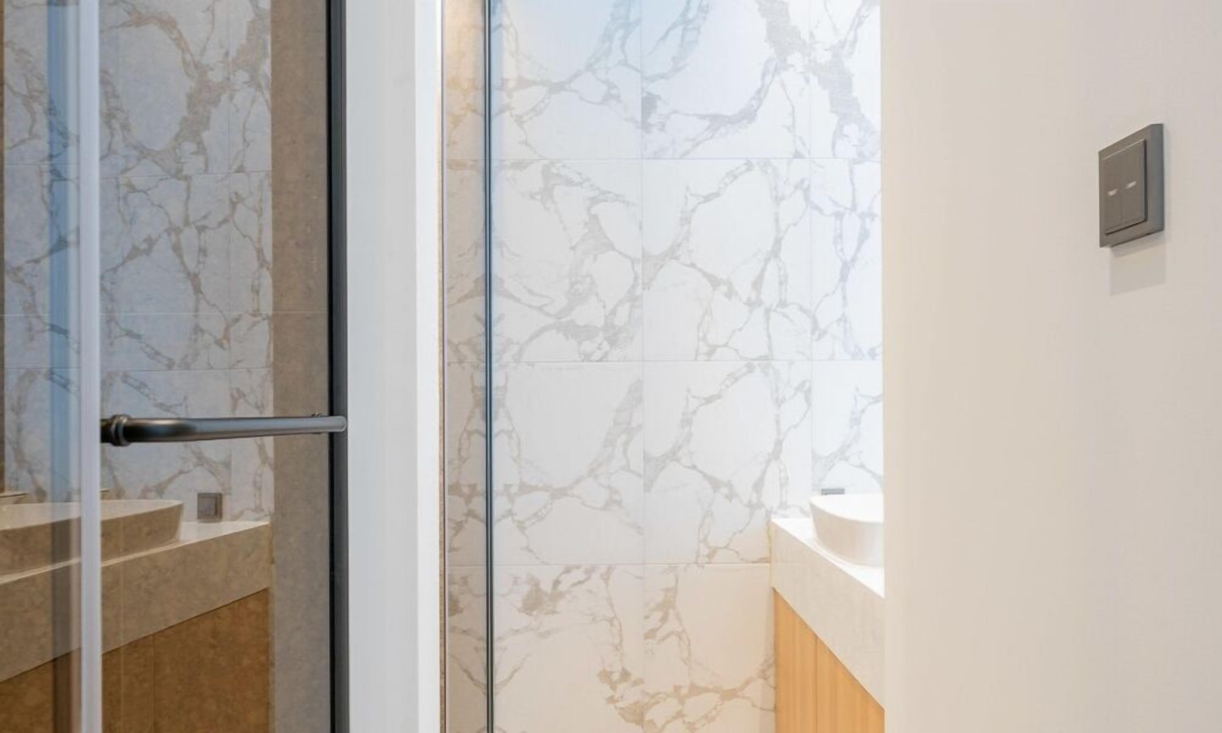 Ein modernes Badezimmer mit Marmorfliesen, einer Duschkabine aus Glas und einem minimalistischen Design.