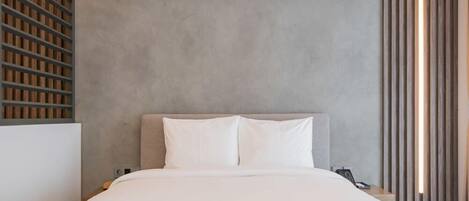 Quarto moderno com cabeceira cinza, roupa de cama branca e painel de parede em ripas de madeira.