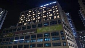 A hotel building with multiple floors, illuminated windows, and signs for 'HOUND HOTEL' and 'GRAND OPEN'. - THE HOUND HOTEL BANDALISLAND 2 (Ansan)