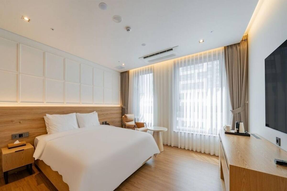 A hotel room with a large bed, a bedside table, a small round table, and a TV.