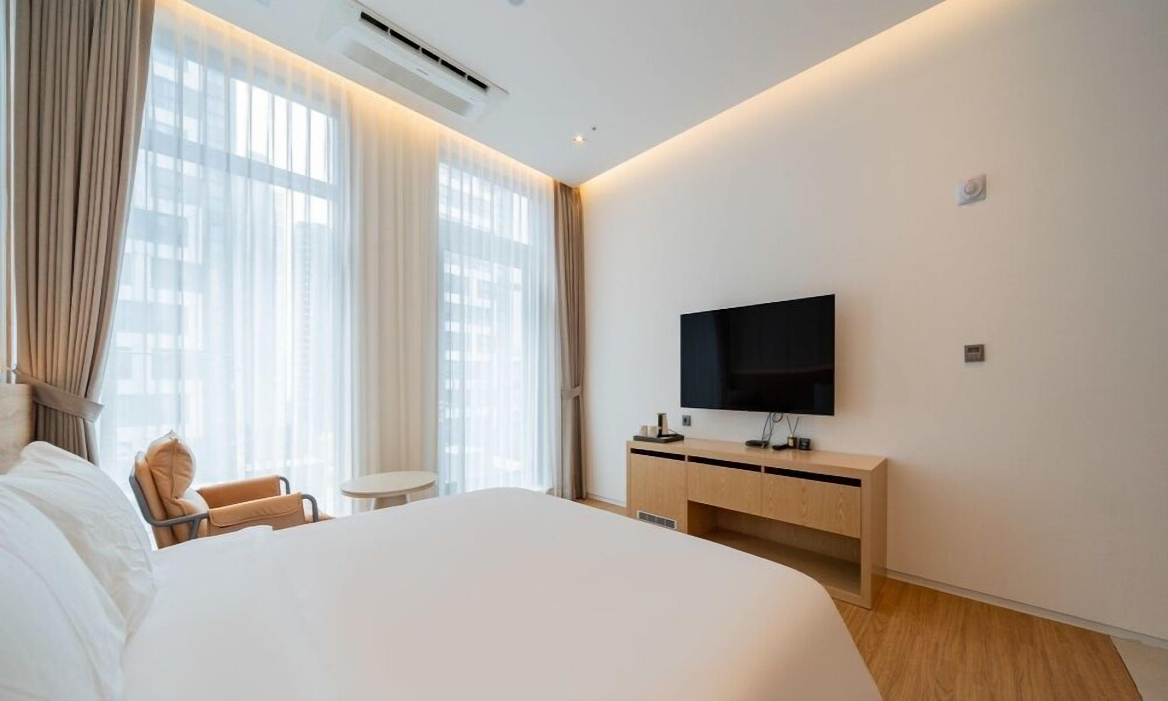 Une chambre d’hôtel avec un grand lit, une télévision, une petite table et une chaise.