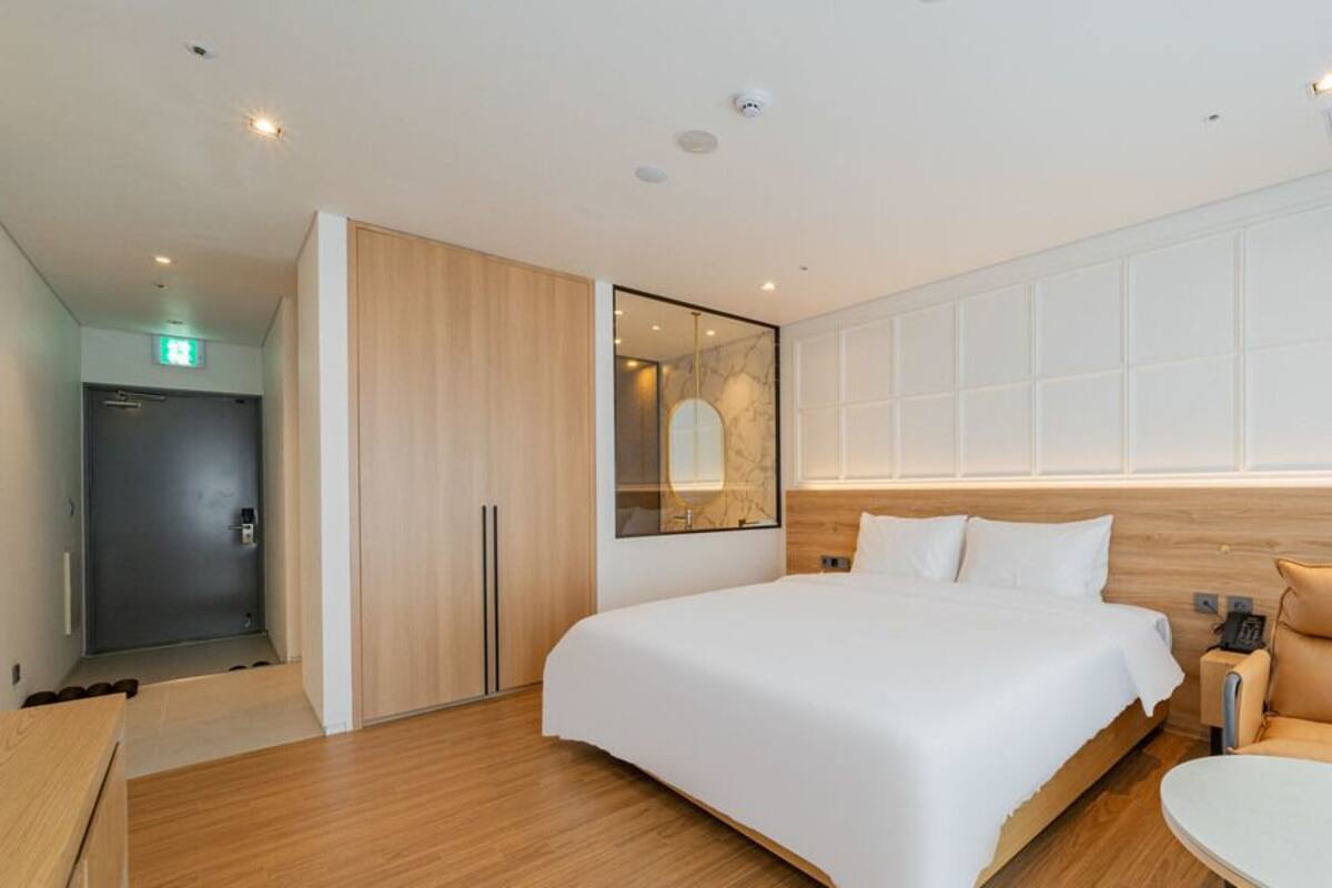 A modern hotel room with a large bed, a seating area, and a mirror.