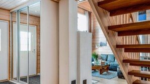 A modern interior with a wooden staircase, a glass door leading to a balcony, and a living area with a sofa and coffee table. - Rukan tunturituuli by Interhome (Kuusamo)