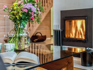 A modern interior with a fireplace, a glass table, and a vase of flowers. - Rukan tunturituuli by Interhome (Kuusamo)
