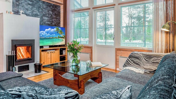 A cozy living room with a fireplace, a television, and large windows. - Rukan tunturituuli by Interhome (Kuusamo)