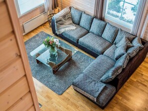 En moderne stue med en hjørnesofa, et sofabord i glas og en dekorativ vase.