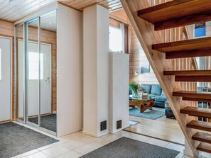 A modern interior with a wooden staircase, a glass door leading to a balcony, and a living area with a sofa and coffee table.