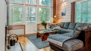 A cozy living room with a sectional sofa, a glass coffee table, and large windows with blinds. - Rukan tunturituuli by Interhome (Kuusamo)
