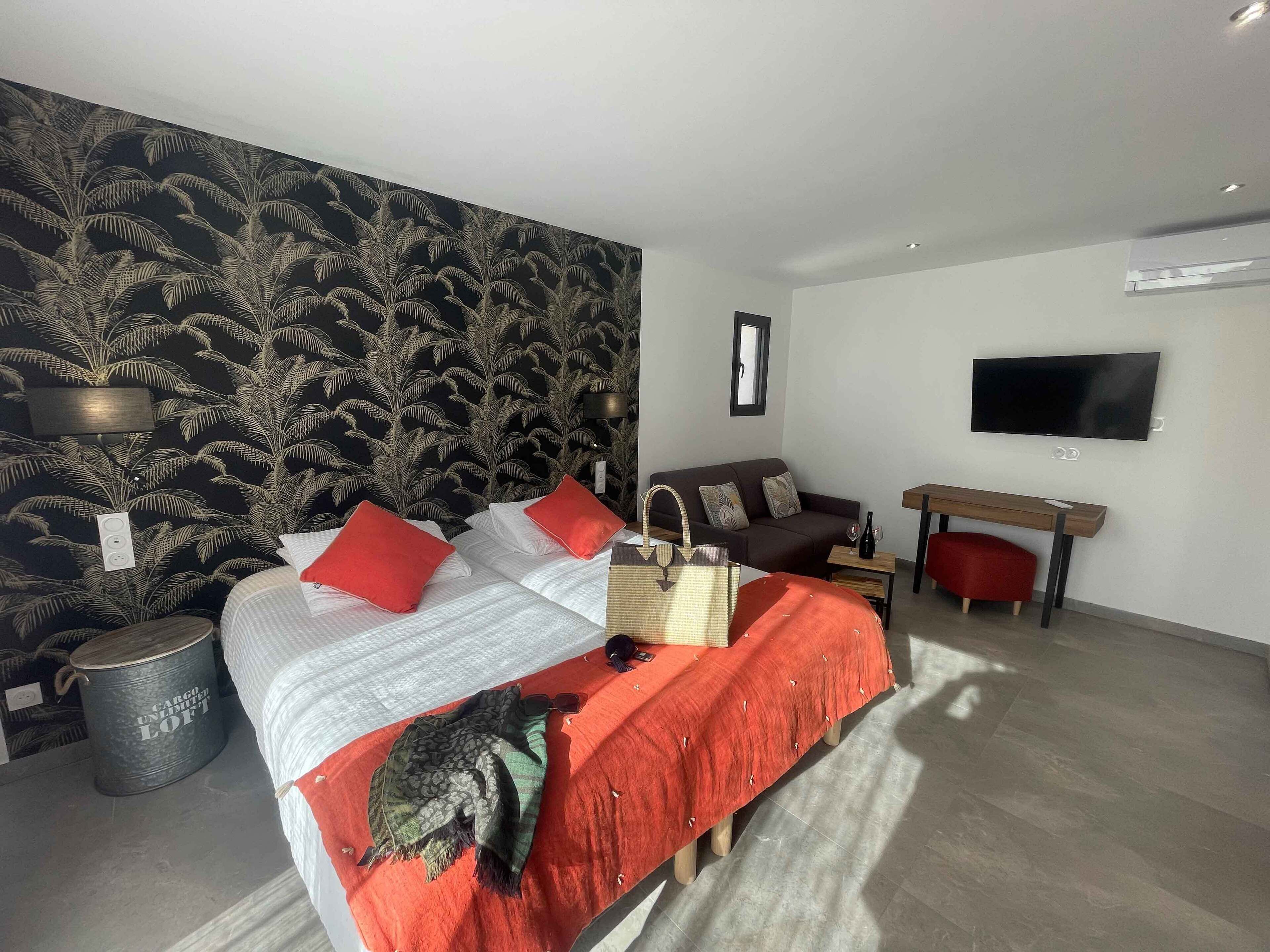 Een moderne hotelkamer met een bed, een slaapbank, een televisie en een bureau.