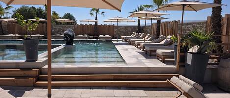 A poolside area with lounge chairs, umbrellas, and a wooden deck.