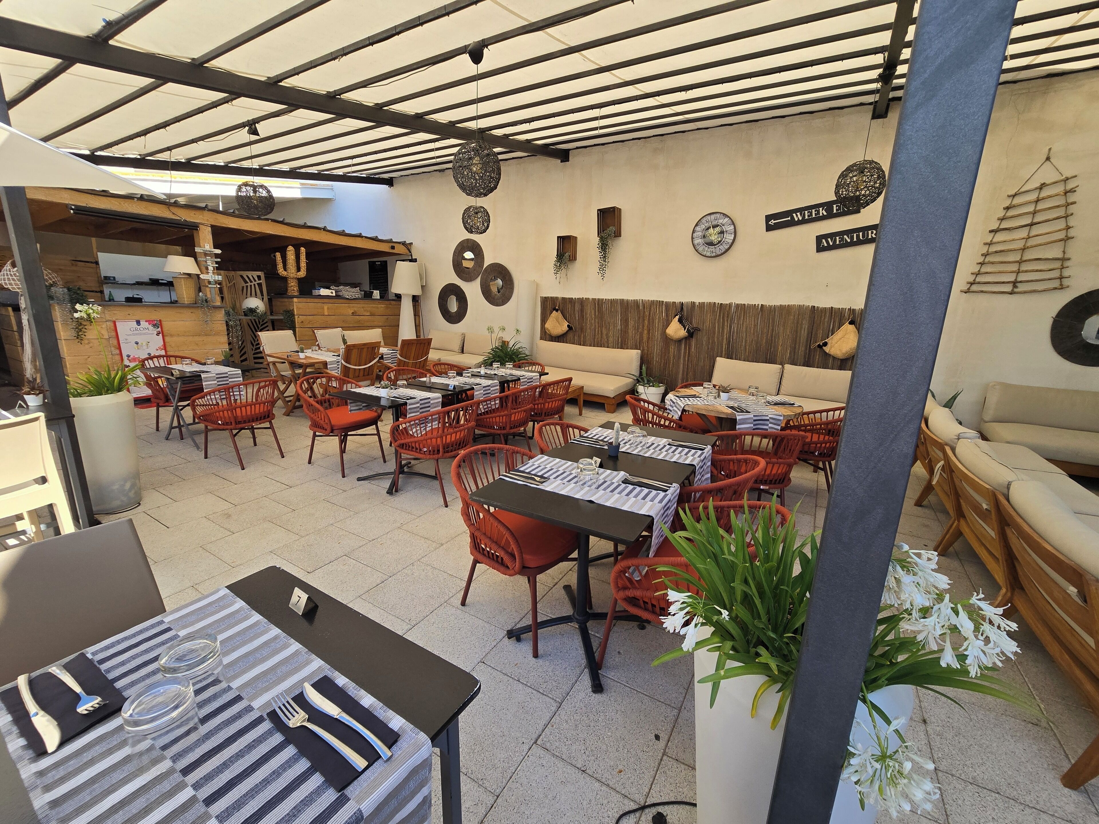 An outdoor seating area with tables and chairs, a sofa, and a clock on the wall.