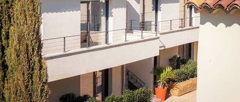 Un edificio de varios pisos con tejado de baldosas, balcones y plantas en macetas.