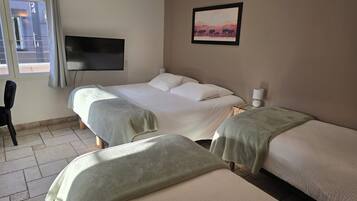 A hotel room with two beds, a TV, a painting, and a window.