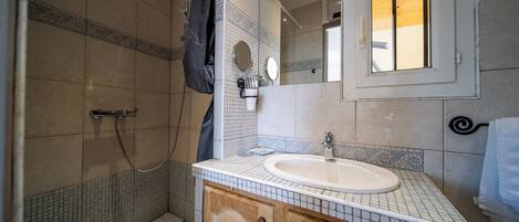 Une salle de bain avec une douche, un lavabo et un miroir.
