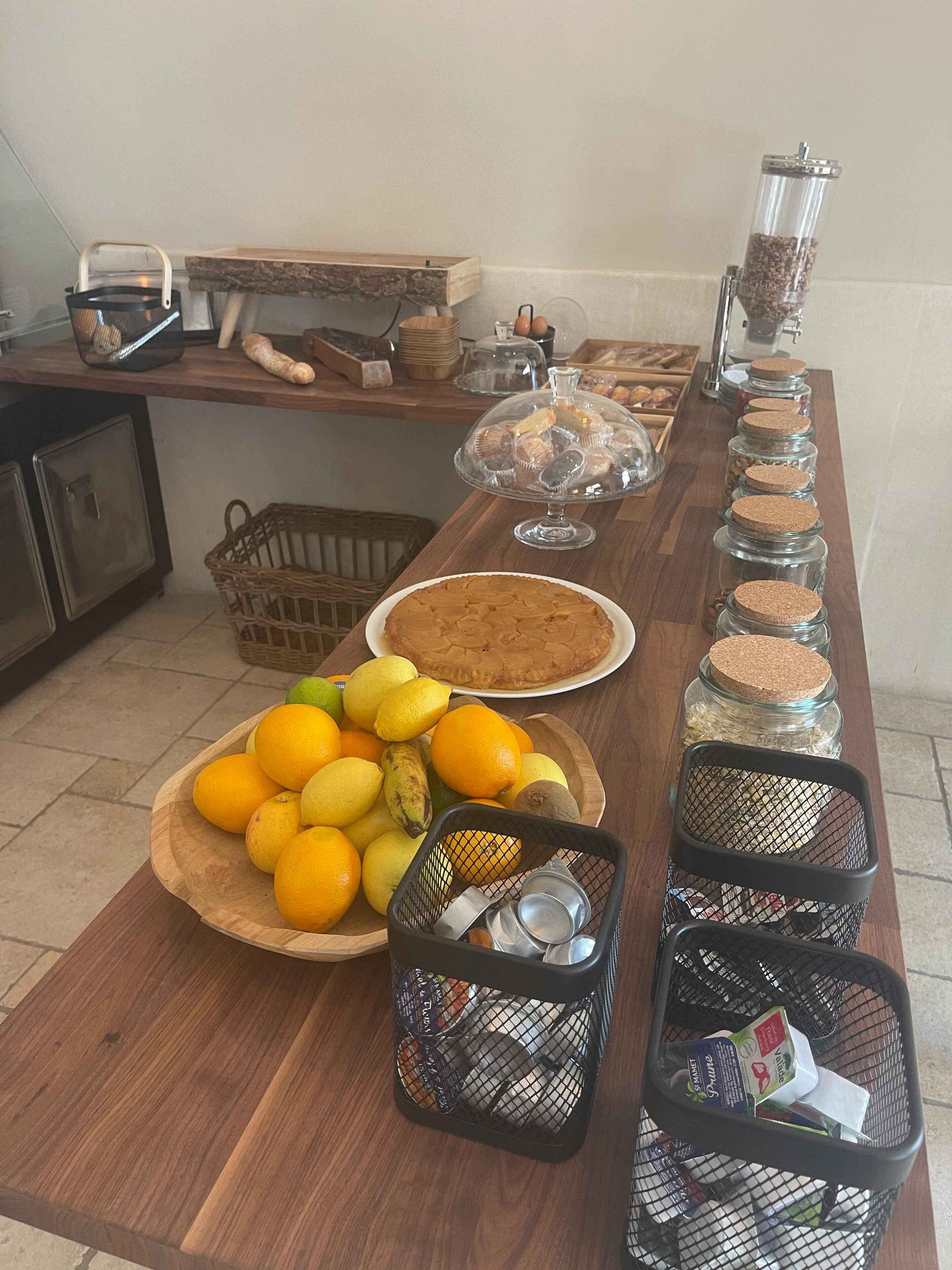 Eine Küchenarbeitsplatte mit verschiedenen Lebensmitteln, darunter ein Kuchen, Zitrusfrüchte und Gläser mit Marmelade.