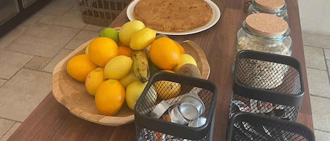 A kitchen counter with a variety of food items, including a pie, citrus fruits, and jars of preserves.