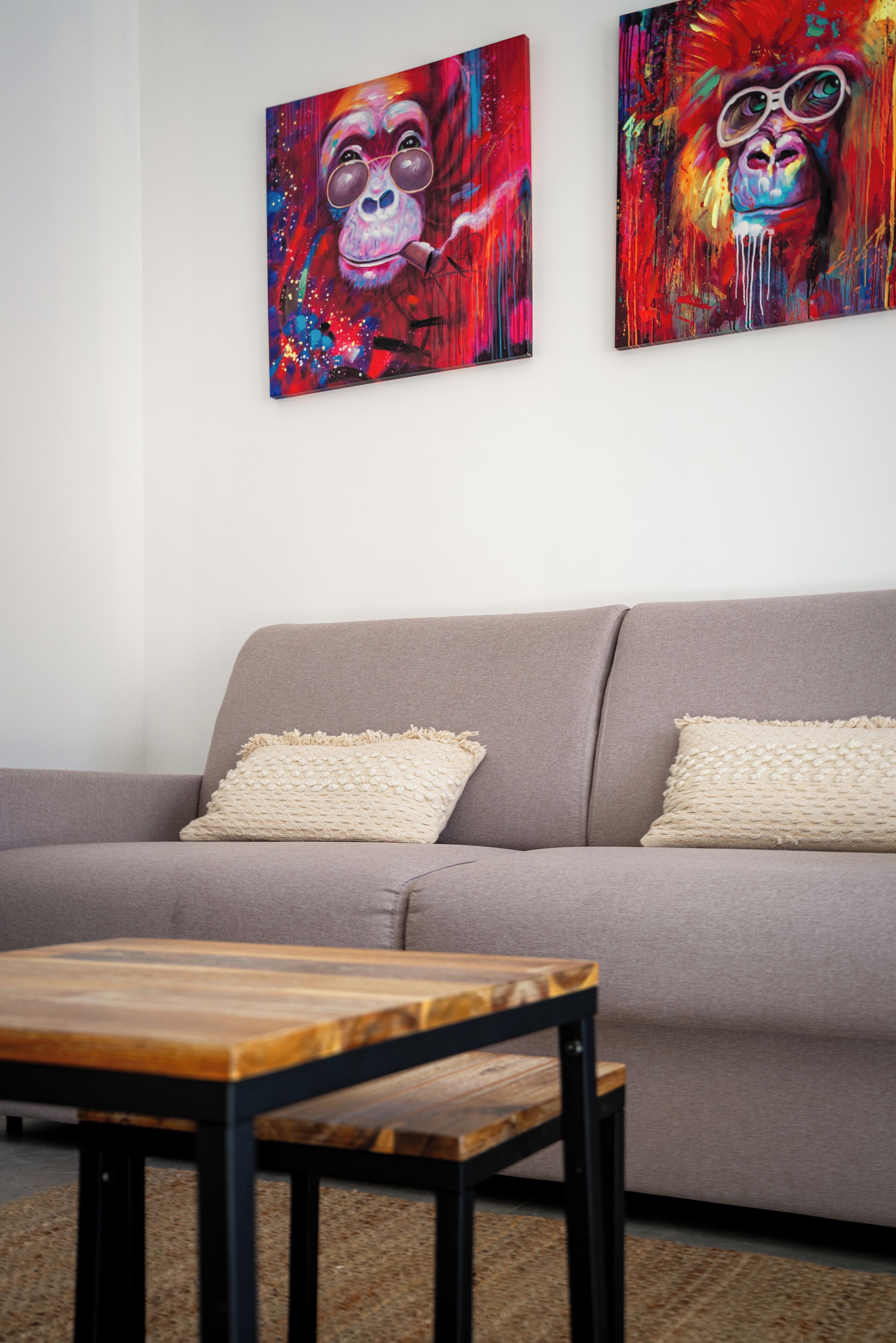 Ein Wohnzimmer mit einem grauen Sofa, zwei beigen Kissen und einem Holztisch.