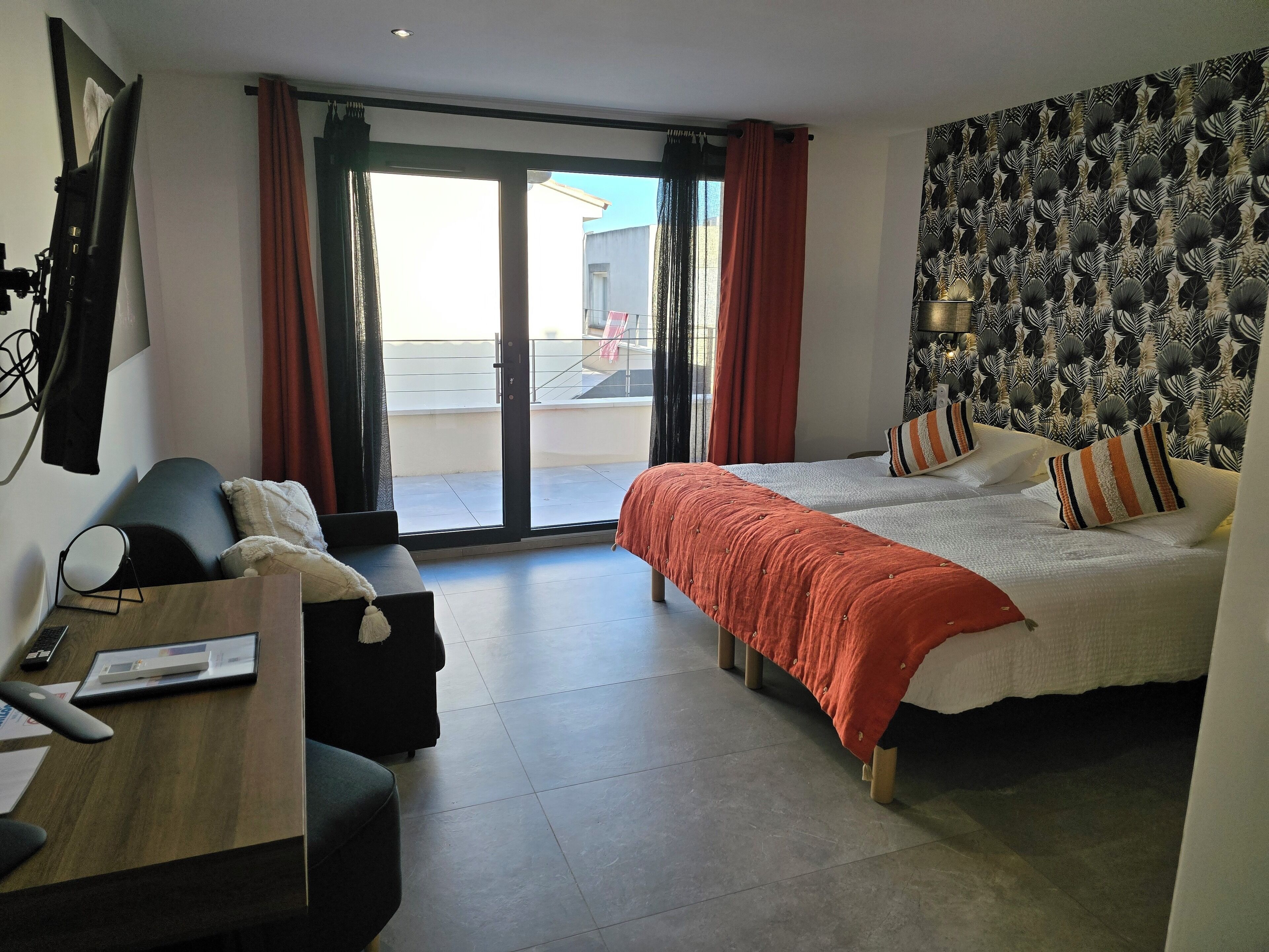 Una habitación de hotel con cama, escritorio, silla y un amplio ventanal.
