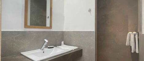 Un baño moderno con un espejo grande, dos lavamanos y una zona de ducha.