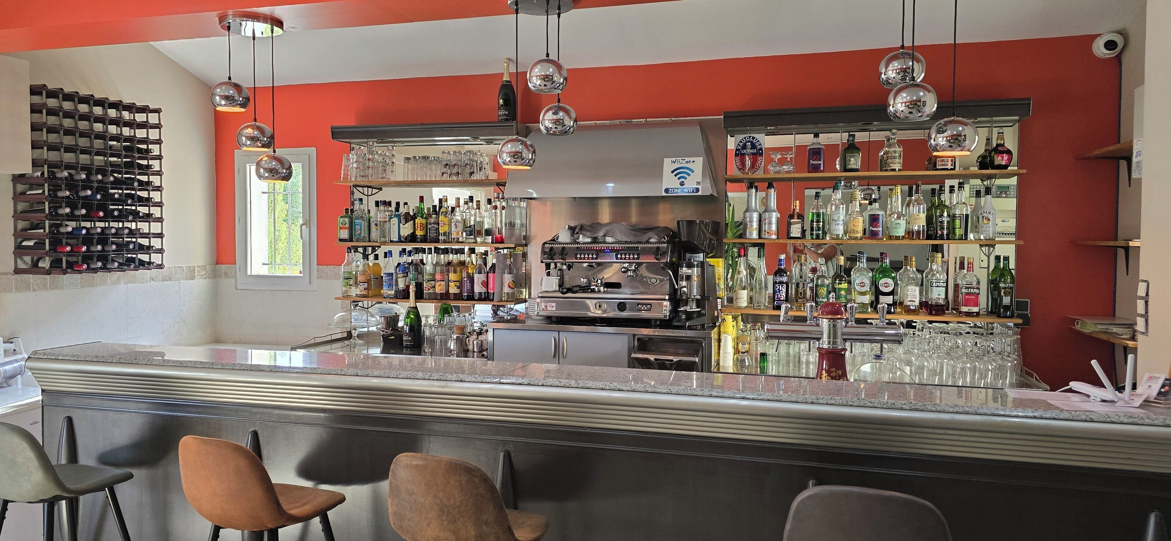 A bar area with a wine rack, shelves of bottles, and a coffee machine.
