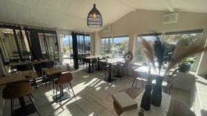 A spacious restaurant with high ceilings, large windows, and a mix of indoor and outdoor seating. - Les Loges du Luberon (Cabrieres-d'Avignon)