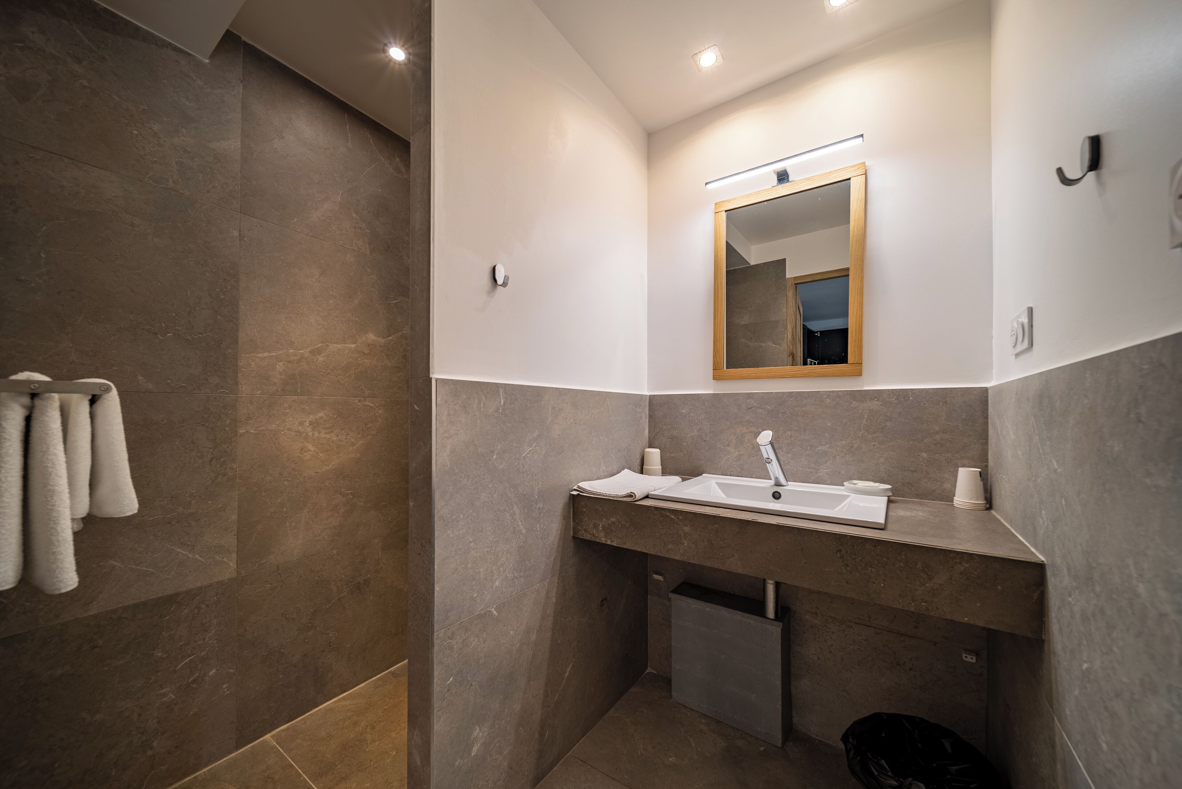 A modern bathroom with a large mirror, a sink, and a towel rack.