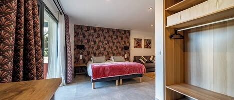 A modern bedroom with a bed, a wooden wardrobe, and a large window with patterned curtains.