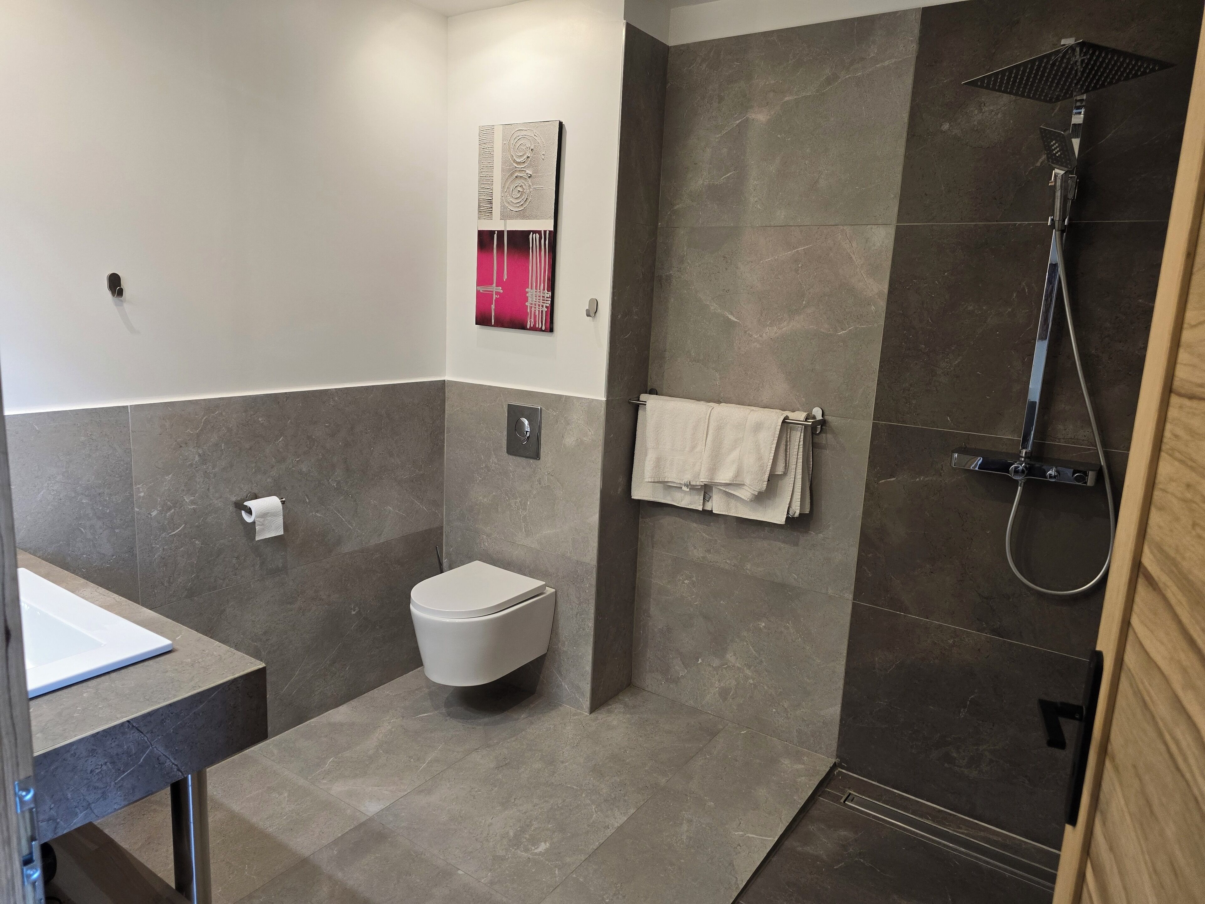 Een moderne badkamer met toilet, wastafel en douche.