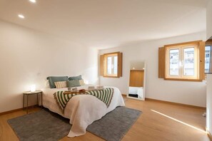 Un dormitorio con cama, mesitas de noche, ventana y espejo.