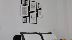 A bedroom with a bed, a nightstand, and framed pictures on the wall. - Appartement Chic et Confortable (Liege)