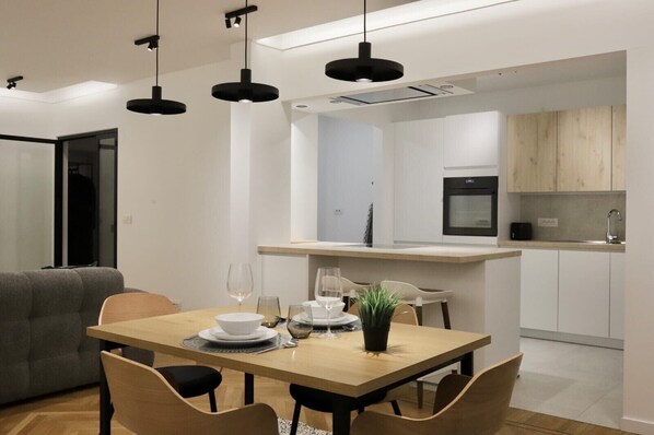 A modern kitchen with white cabinets, a black oven, and a wooden countertop. - Appartement Chic et Confortable (Liege)