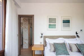 A bedroom with a bed, pillows, a nightstand, and two wall-mounted lamps. - Riviera Vista Luxury Homes -  Hydramis, w/shared Pool (9829+99H Lappei, Greece)