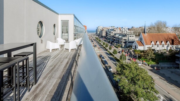 A balcony with a wooden floor, white chairs, and tables.