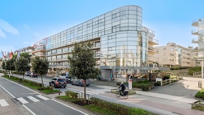 A modern building with a curved glass facade, a pedestrian walkway, and a bike lane.