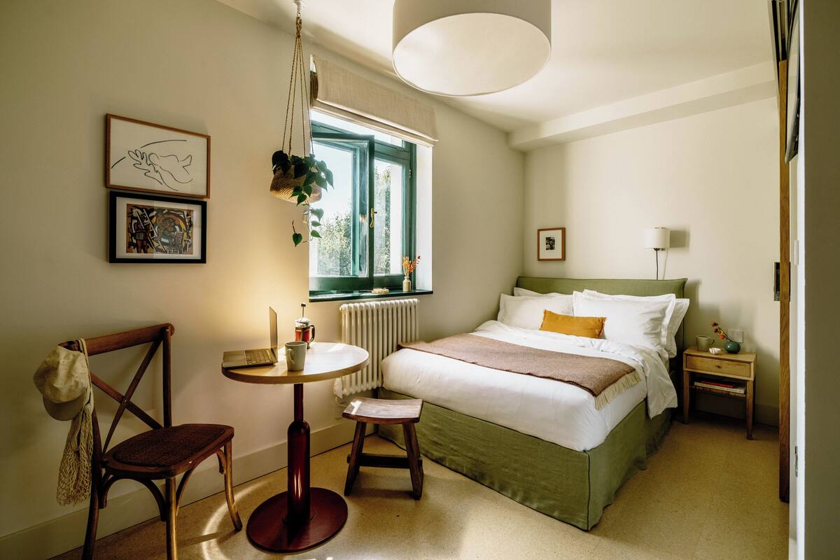 Ein ordentlich eingerichtetes Schlafzimmer mit Bett, Nachttisch, Stuhl und einem kleinen Tisch mit Lampe.