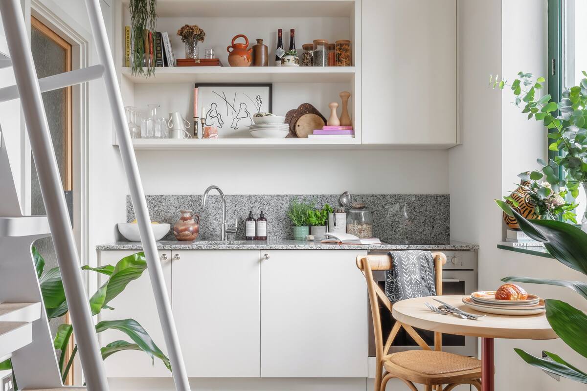 Eine moderne Küche mit weißen Schränken, einer Granitabdeckung und einem Essbereich mit rundem Tisch und Stühlen.