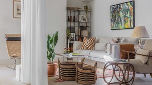 Ein modernes Wohnzimmer mit einem weißen Sofa, einem Couchtisch, Korbwannen und einem Bücherregal.