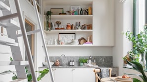 Eine moderne Küche mit weißen Schränken, einer Granit Arbeitsplatte und einer Pendelleuchte.