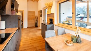A modern kitchen with wooden beams, a dining area with a large window, and a view of the outdoors. - Moiklerhof Apartment (Ramsau im Zillertal)