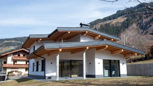 A modern two-story house with a sloped roof, large glass windows, and a wooden balcony. - Moiklerhof Apartment (Ramsau im Zillertal)
