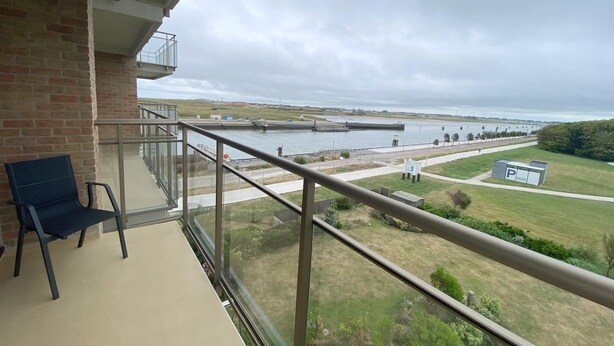 A balcony with a view of a body of water, a grassy area, and a parking sign. - 1 bedroom accommodation in Nieuwpoort (Nieuwpoort)