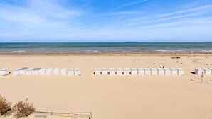 Een strand met witte strandhutten en de oceaan op de achtergrond.