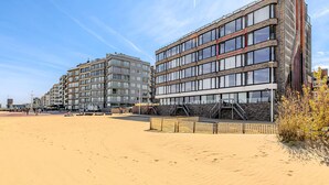 Een hotel aan het strand met meerdere verdiepingen, balkons en een zandstrand.